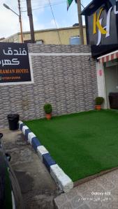 Una pared de ladrillos con un césped verde delante de un edificio. en Kahraman Amman Hotel, en Amán
