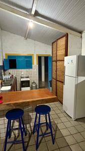 a kitchen with two blue stools and a white refrigerator at Paraíso na Barra de Mamanguape Beira do Rio in Rio Tinto +10 photos