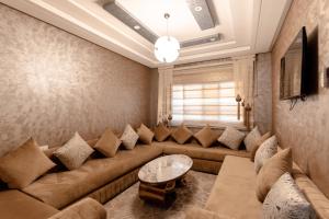 Appart Hôtel Golden Sky Home في بني ملال: غرفة معيشة مع أريكة وطاولة