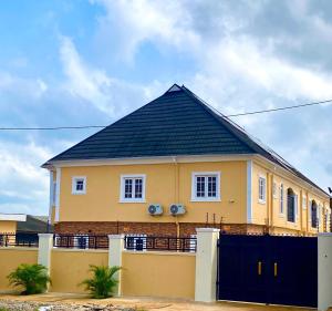 a yellow house with a black roof at Adonai Guesthouse in Agbara