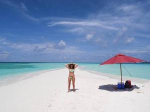 a woman standing on a beach next to an umbrella at Randheli Inn in Maamigili