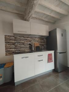 a kitchen with white cabinets and a brick wall at Denisoph Apartment in Lucca +2 photos