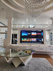 sala de estar con TV grande y mesa de cristal en Ndouha House, en Bafoussam