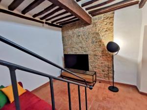 Historic 14th-century apartment in the center of Montaione, Tuscan charm في مونتايون: غرفة معيشة مع تلفزيون وجدار من الطوب