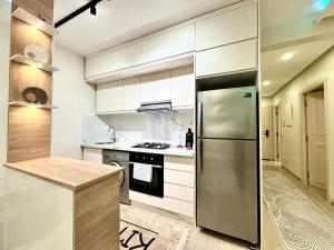 a kitchen with white cabinets and a stainless steel refrigerator at Modern Comfort Studio, la corniche in Mohammedia