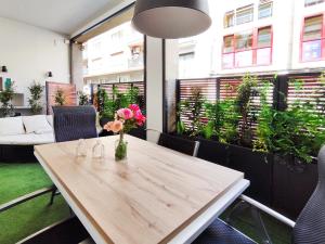 una mesa de madera con flores en una habitación con ventanas en Increíble apartamento de lujo en Terrassa, en Terrassa