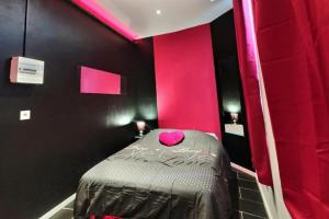 a room with a bed with a pink wall at Les Suites Fénelon in Le Cateau