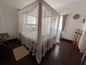 John's Place في أروشا: غرفة نوم مع سرير مظلة مع ستائر بيضاء +3 صور