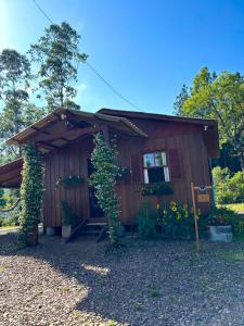 Una pequeña casa de madera con una ventana y algunas plantas. en Pousada dos Sonhos - Timbé do Sul, en Timbe do Sul