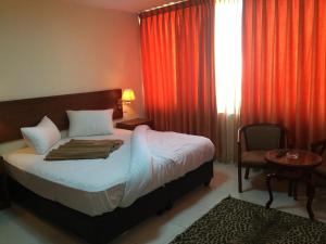 a bedroom with a bed and a window with red curtains at Zaina Plaza Hotel in Amman