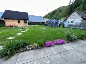 a yard with a dog and some flowers at Family Apartments Myto pod Dumbierom in Mýto pod Ďumbierom