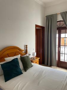 een slaapkamer met een wit bed met groene kussens bij Espera Apartamentos in Espera