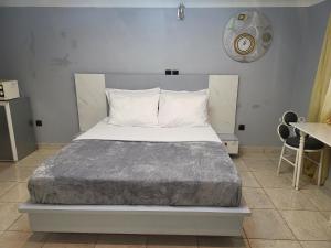 a large bed in a room with a clock on the wall at Ndouha House in Bafoussam