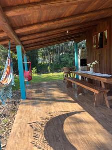 a wooden porch with a picnic table and a hammock at Pousada dos Sonhos - Timbé do Sul in Timbe do Sul