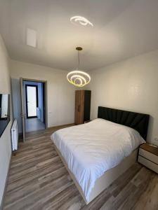 a bedroom with a large white bed and a chandelier at Villa Marhaba in Borjomi