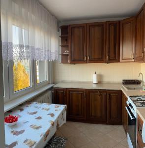 Apartament, mieszkanie 3-pokojowe في كوتنو: مطبخ مع خزائن خشبية وطاولة بداخله