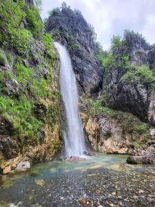 a waterfall in a canyon with a pool of water at Kulla e Gjyshit - Guest House in Theth