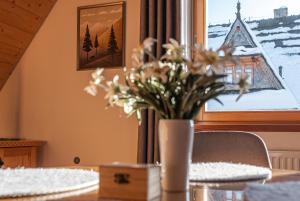 een vaas met bloemen op een tafel voor een raam bij Osada Witów - apartament „Siwa Kopa” in Witów +14 foto's
