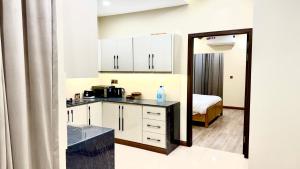 a kitchen with white cabinets and a bed in a room at Executive 2BHK in Zeta Mall in Islamabad