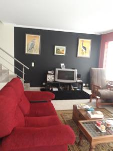 ein Wohnzimmer mit einem roten Sofa und einem Fernseher in der Unterkunft Retiro D'Ouro - Casa inteira in Sendim