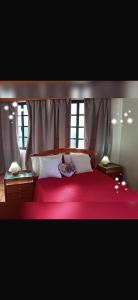 a bedroom with a red bed with two windows at House Silvia & Nuno´s in Machico