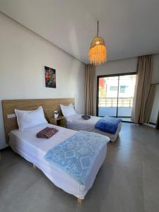 a hotel room with two beds and a chandelier at Atlantic view Tamraght 2 in Tamraght Ou Fella