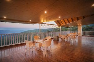 a room with tables and chairs on a balcony at Omaya Vista in Mukteshwar