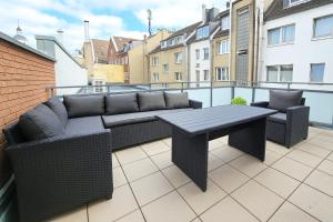 a patio with a couch and a table on a balcony at Old Town Apartments in Düsseldorf