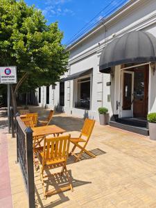 坦迪尔Hotel Francia的庭院配有木桌和椅子以及遮阳伞。