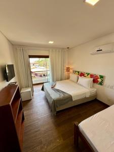 a hotel room with two beds and a balcony at Arraia Suítes Pousada in Pipa