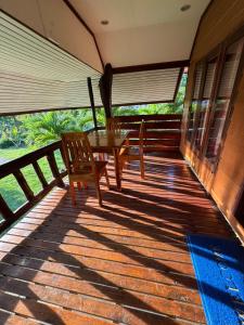 a wooden deck with a table and chairs on it at Family house in Ban Laem Sai
