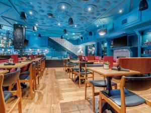 un restaurante con techos azules, mesas y sillas de madera en Hotel Belmont Vancouver - MGallery Collection, en Vancouver