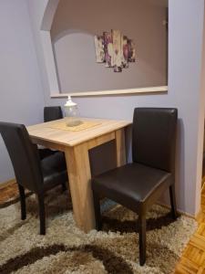 Una mesa de comedor con dos sillas negras y una mesa. en Stan na dan DN-apartman, en Kula 3 fotos más
