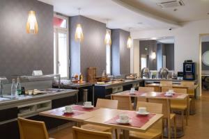 a restaurant with tables and chairs and a kitchen at LOGIS Hôtel de Bourgogne - Mâcon in Mâcon