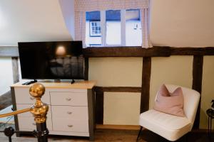 a living room with a television and a white chair at The Cotswold Luxe Cottage in Framlingham
