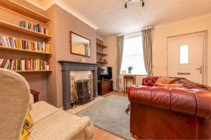 a living room with a leather couch and a fireplace at Charming Cottage in the Heart of Newport - Pass the Keys in Newport