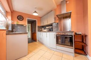 a large kitchen with white cabinets and an oven at Charming Cottage in the Heart of Newport - Pass the Keys in Newport