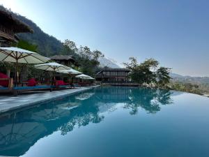 a swimming pool with blue water and umbrellas at Amigo Pu Luong in Làng Bang