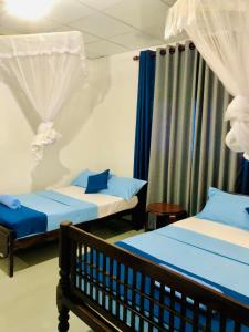 two beds in a room with blue and white at Coco Grove in Galle