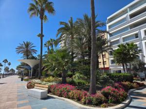 Sea View Penthouse Apartment with Hot Tub - Casa Bella Vista, Buenas Noches , Estepona في إِستيبونا: حديقة فيها نخيل وزهور امام مبنى