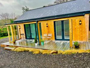 The Jeep House in the Area of Outstanding Natural Beauty في ليسكيرد: كوخ ذو سطح خشبي عليه كراسي