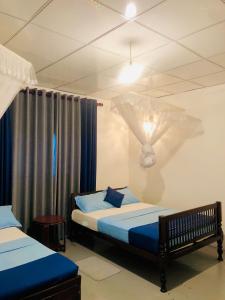 a bedroom with two beds with blue sheets at Coco Grove in Galle