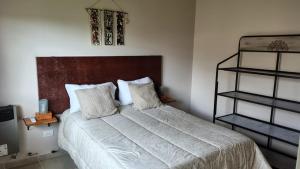 Un dormitorio con una cama grande con cabecero de madera. en Apart Fincas de San Pablo II, en Deán Funes