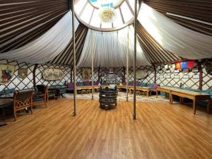 a large tent with a wooden floor and wooden tables at Nomad equestrian Luxury Ger camp in New Ulaanbaatar International Airport