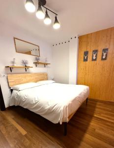 een slaapkamer met een groot wit bed met een houten hoofdeinde bij Courmayeur La Maison des Amis in Courmayeur +5 foto's