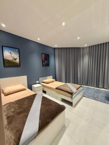 a bedroom with two beds and a blue wall at Abu Rakan Apartment in Muscat