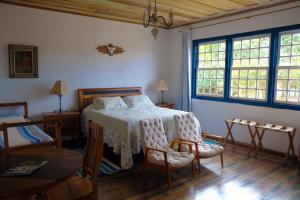 1 dormitorio con 1 cama, mesa y sillas en Tiradentes Pousada Ramalhete, en Tiradentes