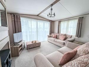 Stunning 8 Berth Caravan With Decking At Kessingland Beach Ref 90017D في Benacre: غرفة معيشة مع أريكة وتلفزيون