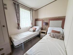 Stunning 8 Berth Caravan With Decking At Kessingland Beach Ref 90017D في Benacre: غرفة صغيرة بها سريرين ونافذة +19 صورة