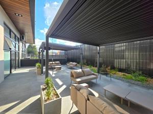 a patio with couches and tables on a building at Departamento Nuevo 1D1B con estacionamiento sobre stripcenter y supermercado in Los Ángeles
